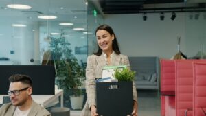 Employee carrying a box of belongings as she leaves the office on her last day
