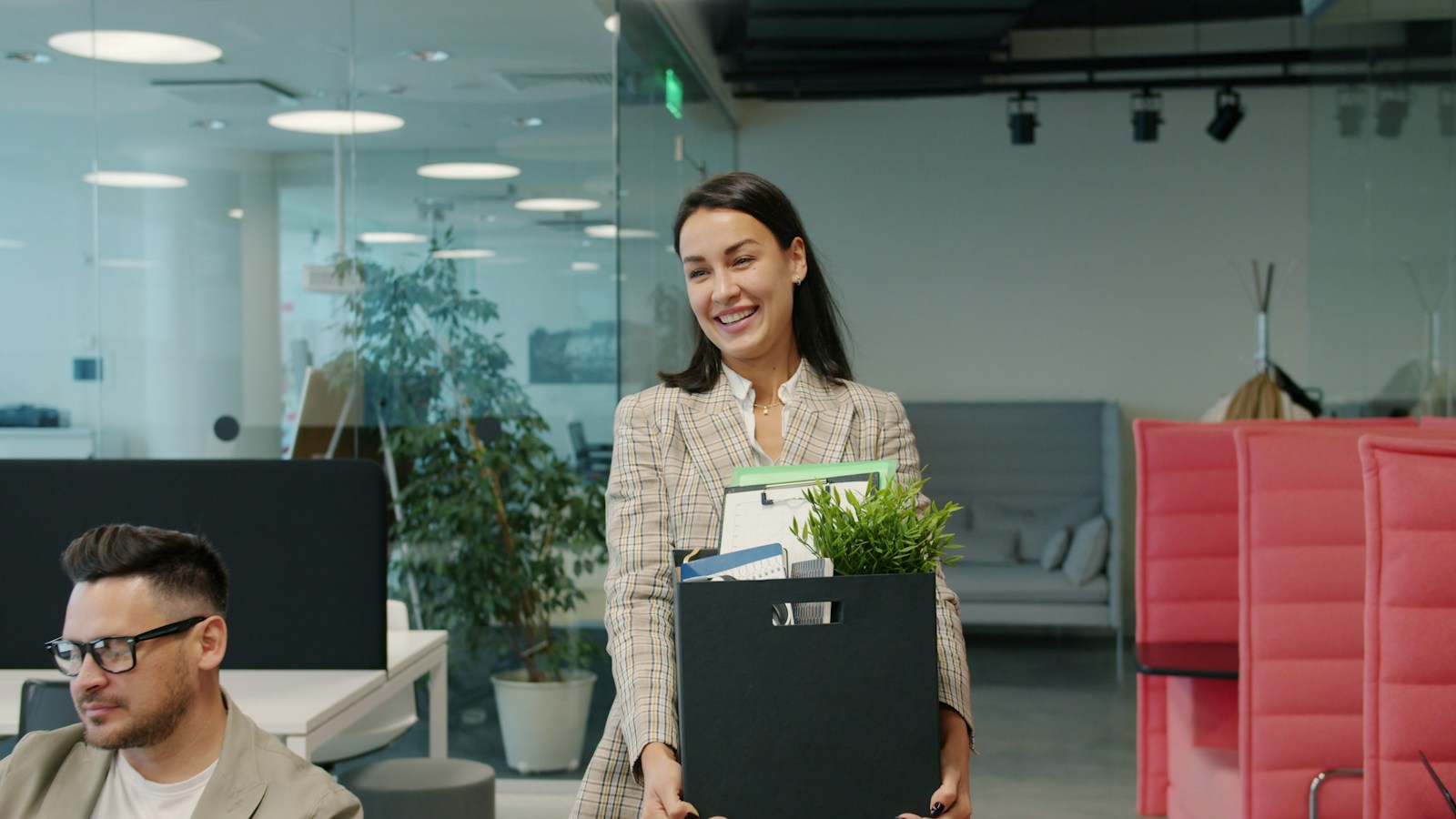 Employee carrying a box of belongings as she leaves the office on her last day
