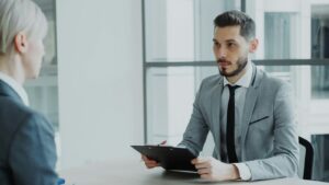 Manager reviewing notes on a clipboard during a meeting with an employee
